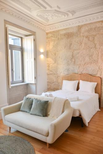 a bedroom with a bed and a couch and a wall at Lindo, funcional e charmoso espaço - Porto - APT H in Porto