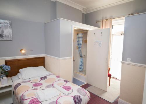 um pequeno quarto com uma cama e uma janela em Midland Hotel em Weston-super-Mare