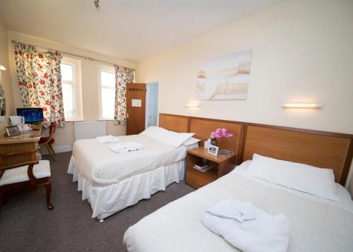 a hotel room with two beds and a desk at Midland Hotel in Weston-super-Mare