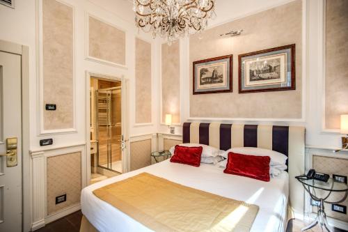 a bedroom with a large bed with two red pillows at The Britannia Hotel in Rome