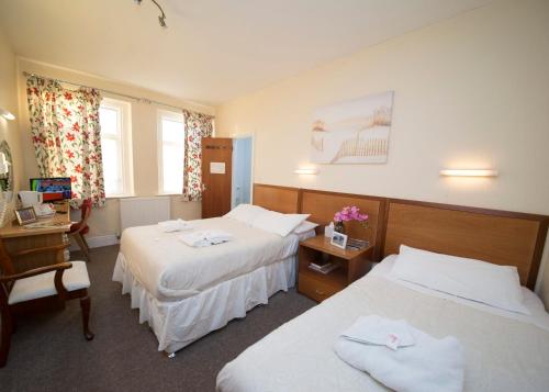 a hotel room with two beds and a desk at Midland Hotel in Weston-super-Mare