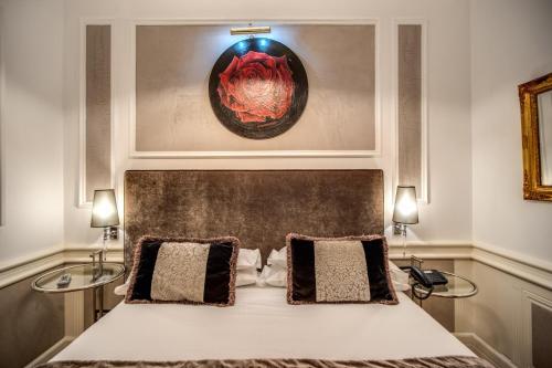 a bedroom with a bed with two lamps and a painting at The Britannia Hotel in Rome