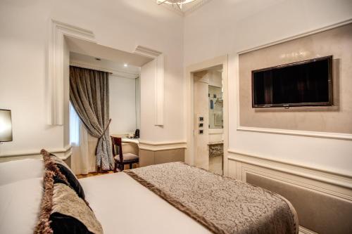 a hotel room with a bed and a flat screen tv at The Britannia Hotel in Rome