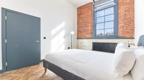 a bedroom with a white bed and a brick wall at No 1 at Simpson Street Apartments Sunderland in Sunderland