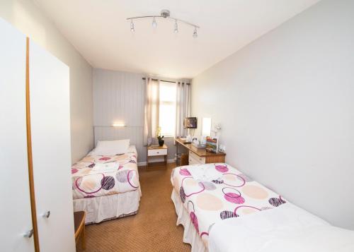 Habitación de hotel con 2 camas y escritorio en Midland Hotel, en Weston-super-Mare