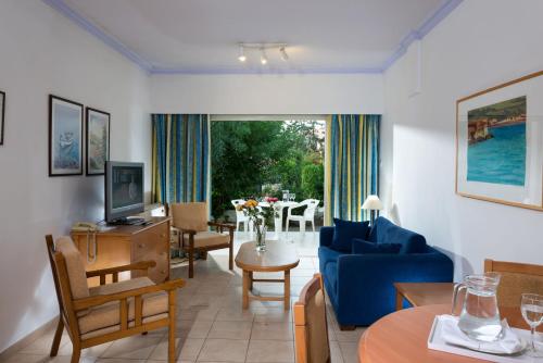 a living room with a blue couch and a table at Paphos Gardens Holiday Resort in Paphos