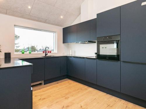 a large kitchen with black cabinets and a window at 10 person holiday home in Bogense-By Traum in Bogense