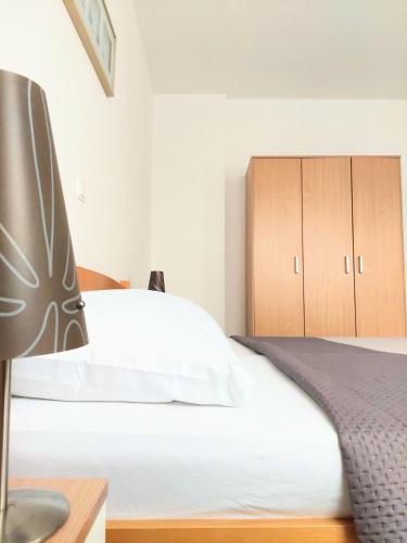a bedroom with a white bed and wooden cabinets at Apartments Dia in Zaostrog
