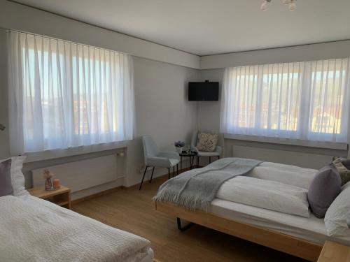 a bedroom with two beds and a tv and windows at Hotel B&B Stossplatz in Appenzell