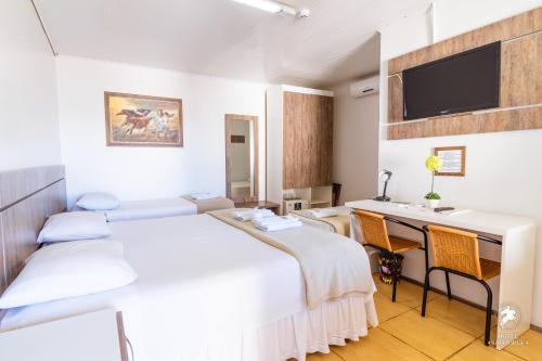 a room with a bed and a desk with a computer at Hotel São Jorge in Alegrete