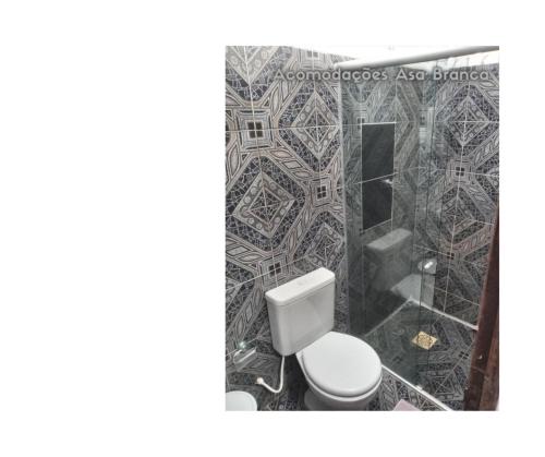 a bathroom with a toilet and a tiled wall at Pousada Asa Branca in Soure