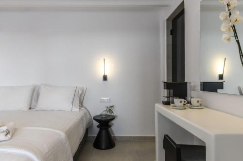 a white bedroom with a bed and a desk at Sunset Windmills Suites in Mýkonos City