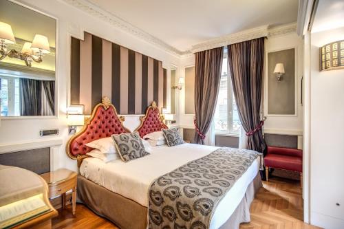 ローマにあるザ ブリタニア ホテルのベッドと赤い椅子が備わるホテルルームです。