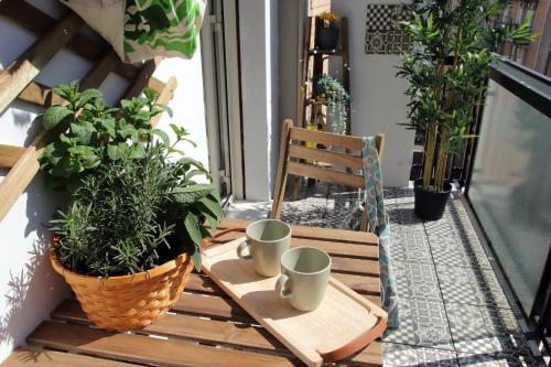 - une table en bois avec deux tasses sur un balcon orné de plantes dans l'établissement MonteVERDE MAISON, à Rome