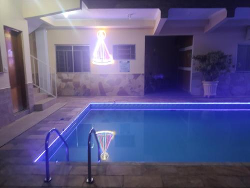 a swimming pool at night with a basketball hoop in a house at Hotel Pousada Recanto da Madá in Aparecida