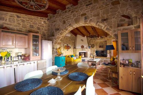 a kitchen and living room with a large stone wall at Stonehouse Olivelia - Afrathias Beach in Tympáki