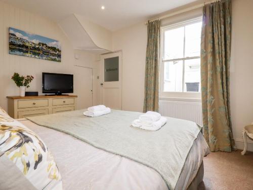 Un dormitorio con dos camas y un televisor y una ventana. en Driftwood, en Fowey