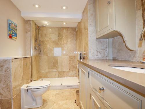 Un baño con inodoro, lavabo y ducha. en Driftwood, en Fowey