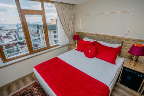una camera da letto con un letto con cuscini rossi e una finestra di Gülec Konak Hotel a Istanbul
