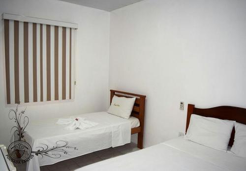 um pequeno quarto com 2 camas e uma janela em Pousada Santos em Parintins