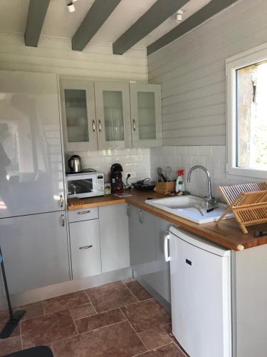 una cocina con armarios blancos y fregadero en Maison au bord de riviere , proche de la mer- spa semi rigide plein air en option, en Bacqueville-en-Caux