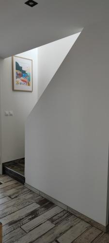 a living room with white walls and wood floors at Les terrasse du rody, vue mer . in Guipavas