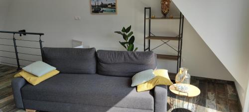 a living room with a gray couch and a table at Les terrasse du rody, vue mer . in Guipavas
