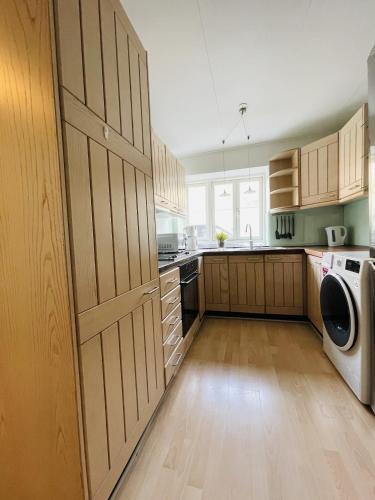 a kitchen with wooden cabinets and a washer and dryer at aday - Central Studio Apartment in Aalborg