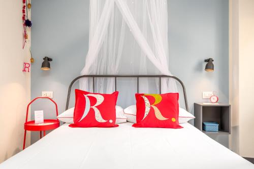 ein Schlafzimmer mit einem weißen Bett mit roten und gelben Kissen in der Unterkunft Carugio Remilde in La Spezia
