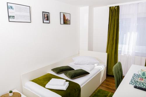 a white bedroom with a bed and a table at Pensiunea Pictorilor in Baia Mare