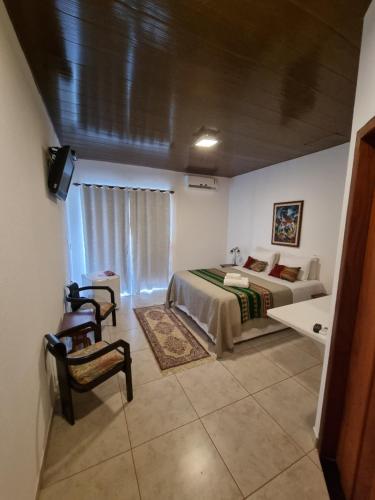 a bedroom with a bed and a chair in a room at Pousada Ikabana in Pirenópolis