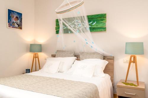 a bedroom with a bed with white sheets and blue lamps at Carugio Remilde in La Spezia