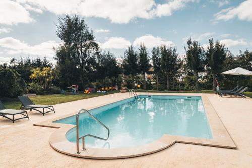 a swimming pool in a resort with chairs and trees at Vale Pisco in Bombarral