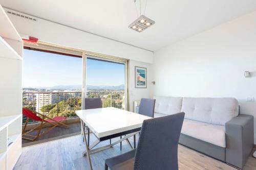 a living room with a white couch and a table at Studio with a panoramic view at the last floor of the residence with a pool in Antibes
