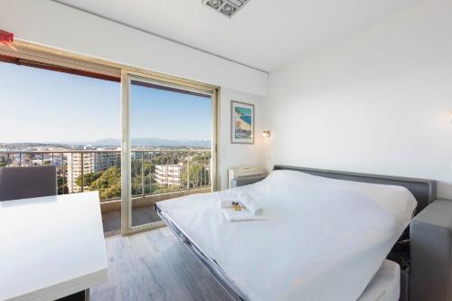 une chambre avec un lit et une grande fenêtre dans l'établissement Studio with a panoramic view at the last floor of the residence with a pool, à Antibes