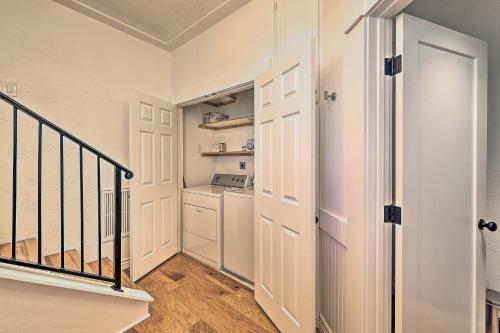 a hallway with a staircase and a kitchen with white cabinets at Ridgeline Retreat with Mountain Lake Views! in Lake Arrowhead