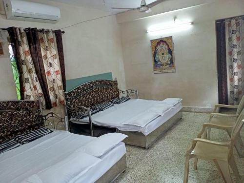 a room with two beds and a chair in it at Stay Goa Guesthouse in Madgaon