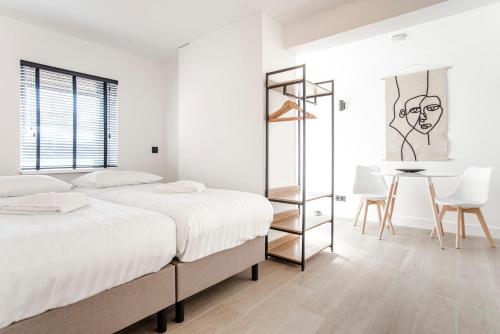 ein weißes Schlafzimmer mit 2 Betten und einem Tisch in der Unterkunft La Casa de Verano I in Zandvoort