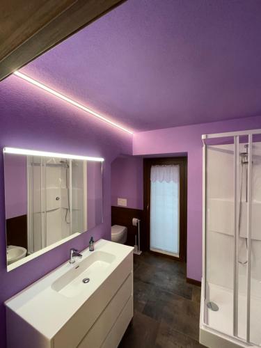 y baño con paredes de color púrpura, lavabo y ducha. en Casa Carral, en Aymavilles