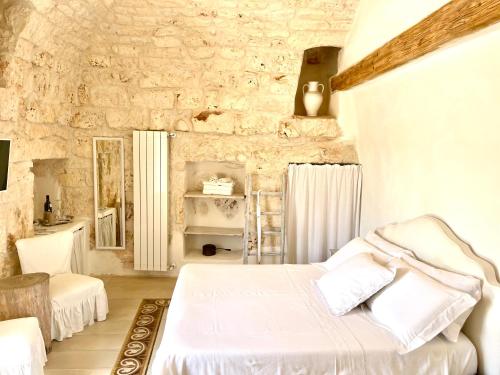 a bedroom with a white bed and a stone wall at Relais Grottone in Ostuni