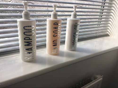 three white bottles sitting on a window sill at Lovely little flat by the sea in Cleethorpes in Cleethorpes