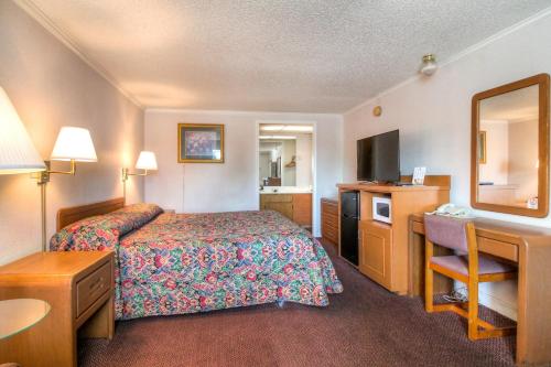 a hotel room with a bedroom with a bed and a desk at Corbin Inn in Corbin