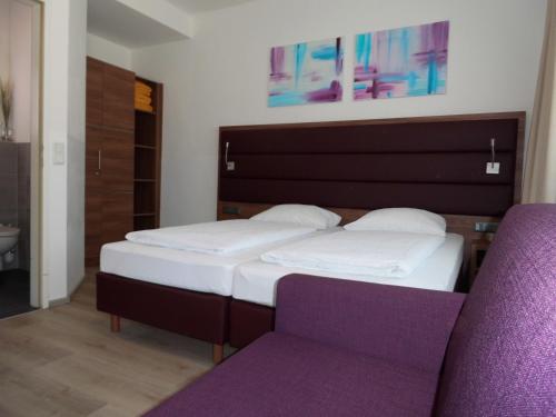 a bedroom with two beds and a purple chair at Pension Elisabeth - Rooms & Apartments in Salzburg