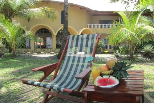 a rocking chair with a bowl of fruit on a table at Hotel Delfin Playa Bejuco in Esterillos Este