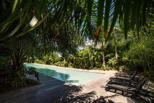 a swimming pool with lounge chairs and palm trees at 87978 DELUXE and unique 3BR condo by The Harbor, Via Montejo in Mérida