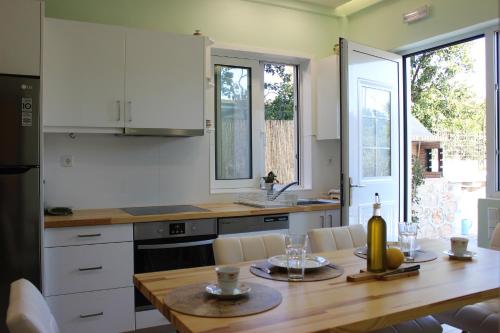 een keuken met een houten tafel en witte kasten bij Minas new apartment 2mins walking from Stoupa beach in Stoupa