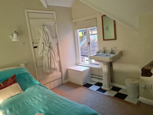 y baño con cama, lavabo y espejo. en Beggar's Lane Cottage en Winchester