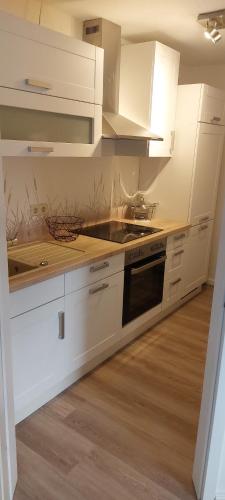 uma cozinha com armários brancos e um forno com placa de fogão em Ferienwohnung im Bauernhaus em Gallin