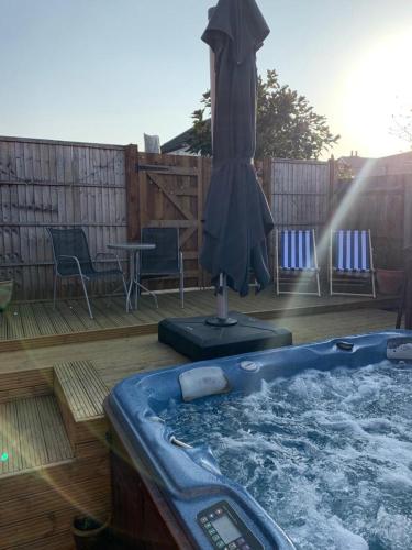 a hot tub on a deck with an umbrella at The Forge Guest Rooms in Long Whatton