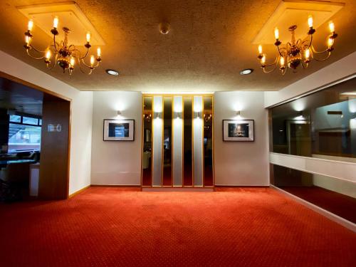 un couloir avec moquette rouge et portes en verre dans l'établissement Livermead Cliff Hotel, à Torquay